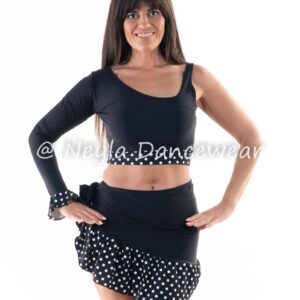 Bailarina con conjunto negro para danza del vientre, compuesto por top asimétrico y falda corta con volantes de lunares, en pose de estudio.